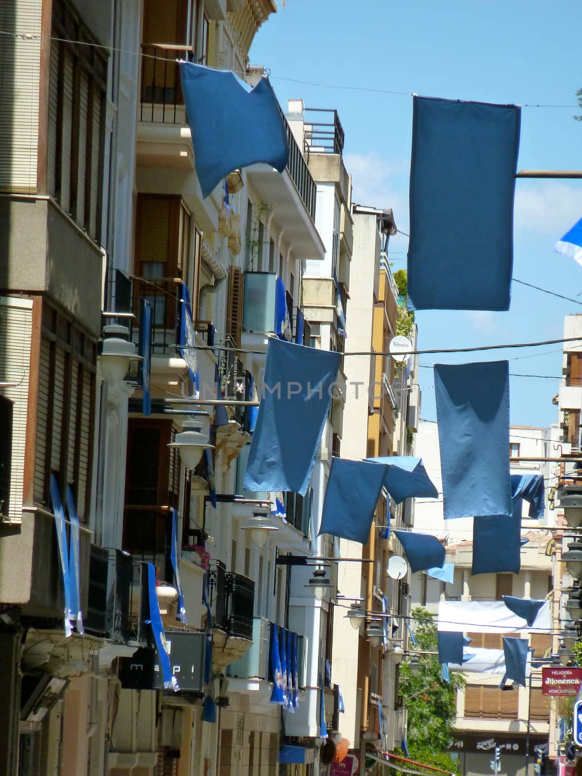 blue flags hanging in a street for a fiesta