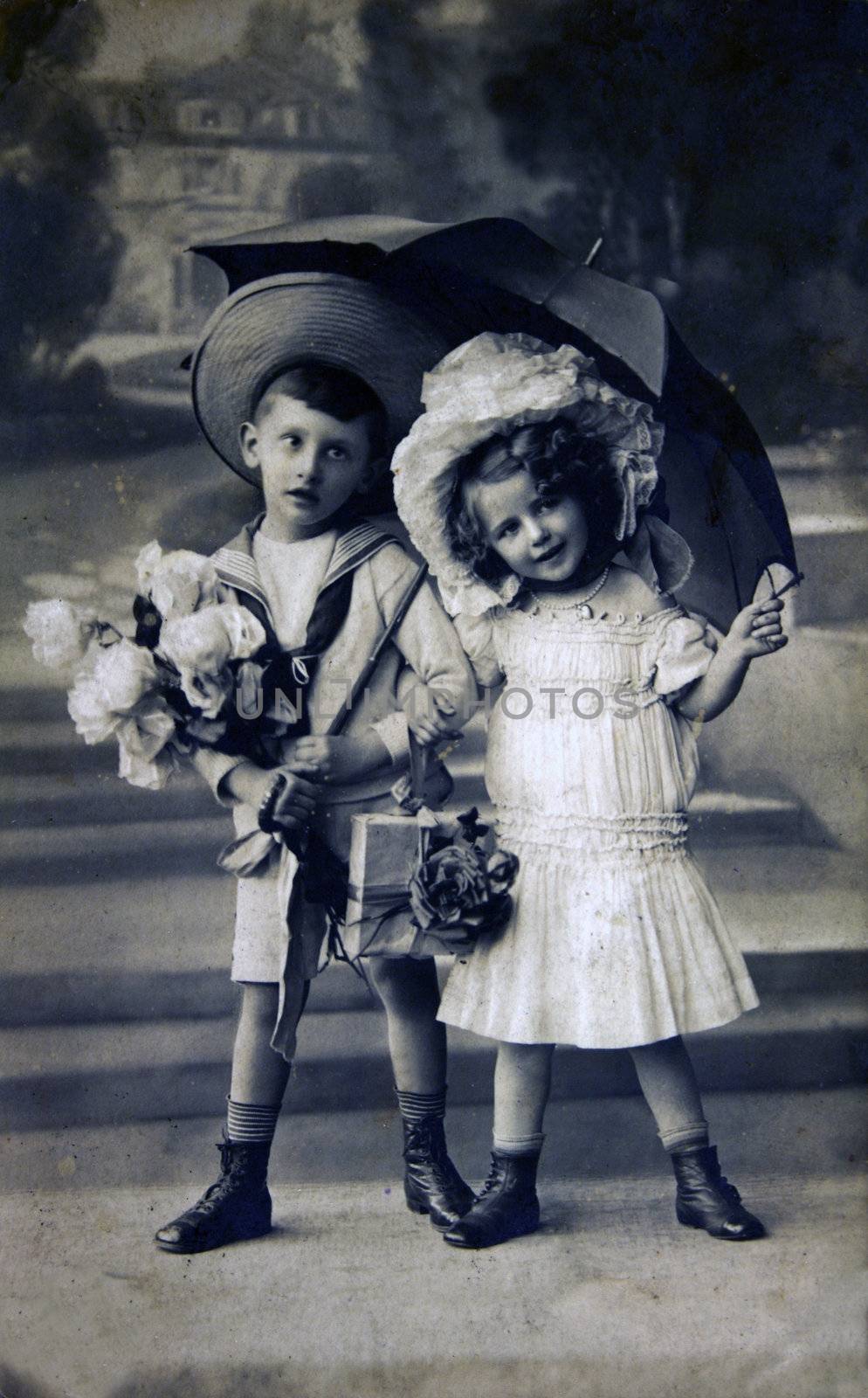 GERMANY - CIRCA 1909: Postcard printed in the Germany shows boy and girl under an umbrella, circa 1909