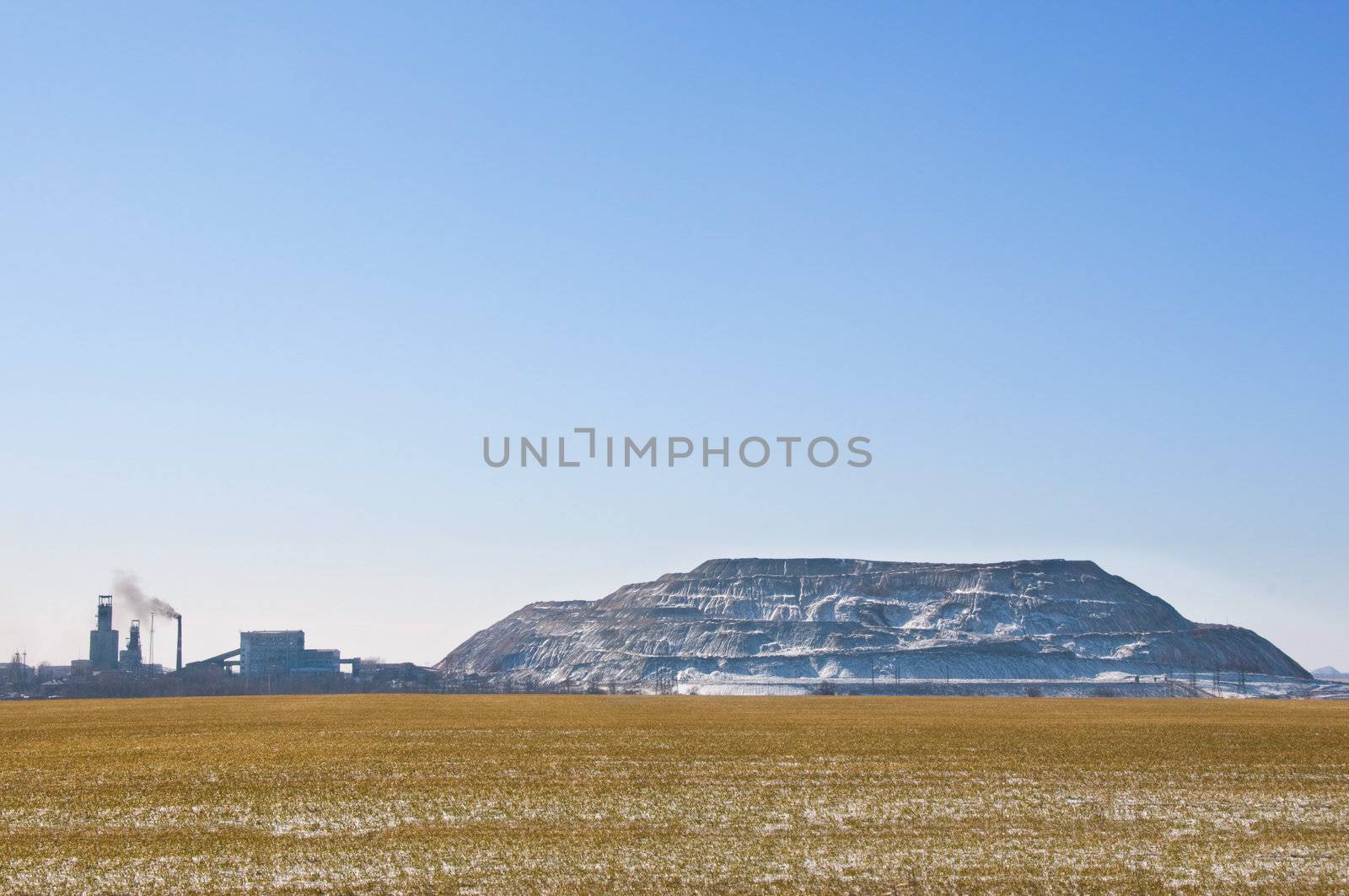 Artificial man-made rock near coal mine in Ukraine with winter field on foreground