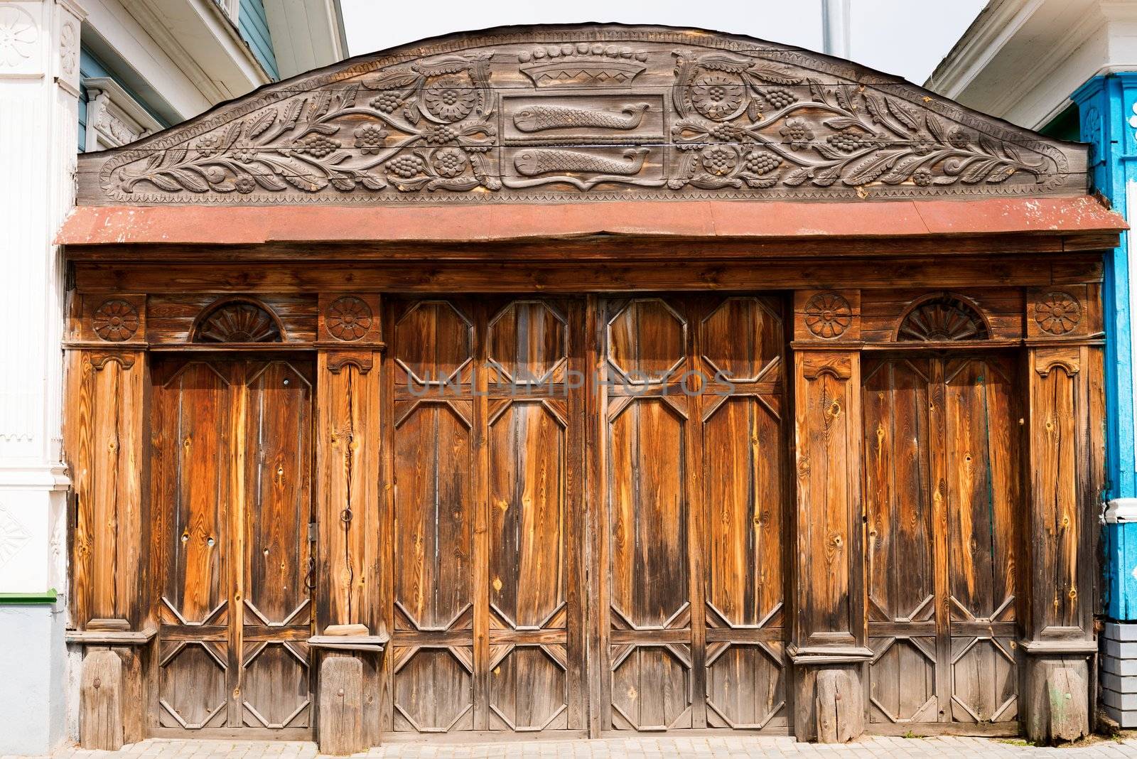 Old closed wooden ornate gate, with symbols on the top