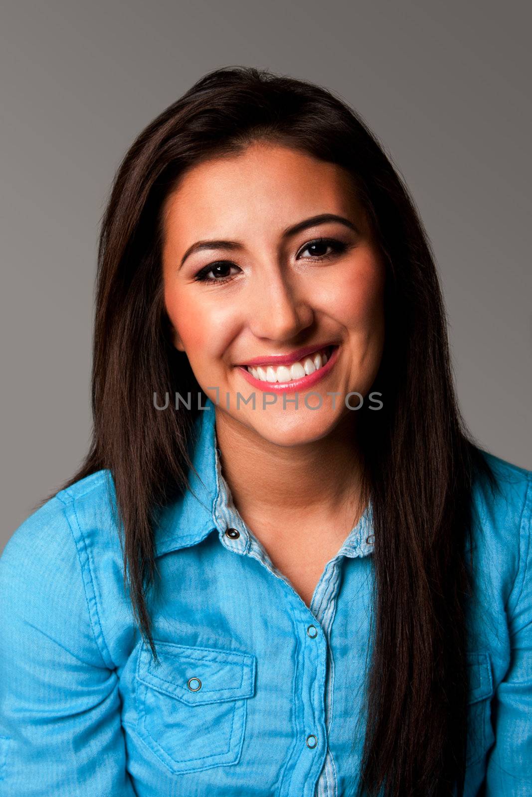 Happy beautiful smiling female student portrait of face with long hair on gray.