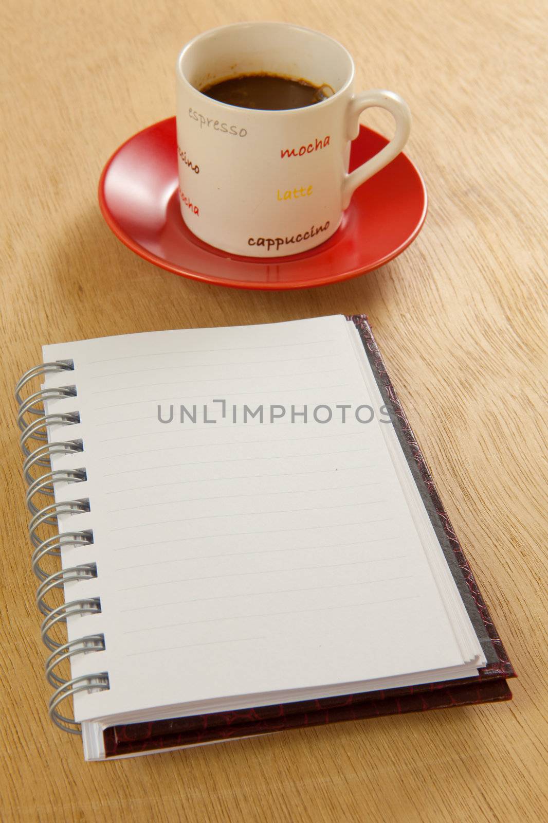 red cup of hot coffee and book on wood background