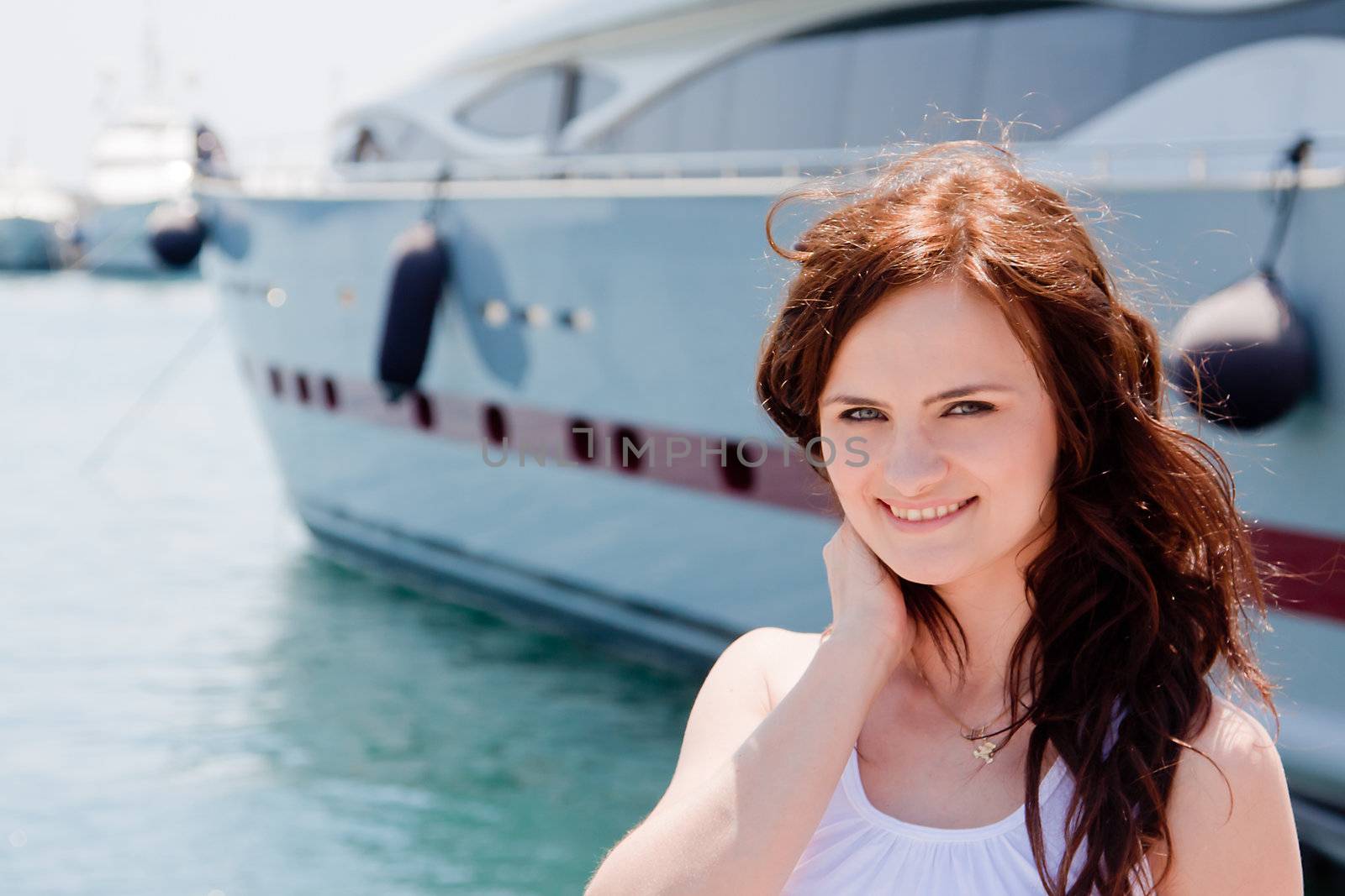 Photo of a young and beautiful girl against the backdrop of yachts in the port