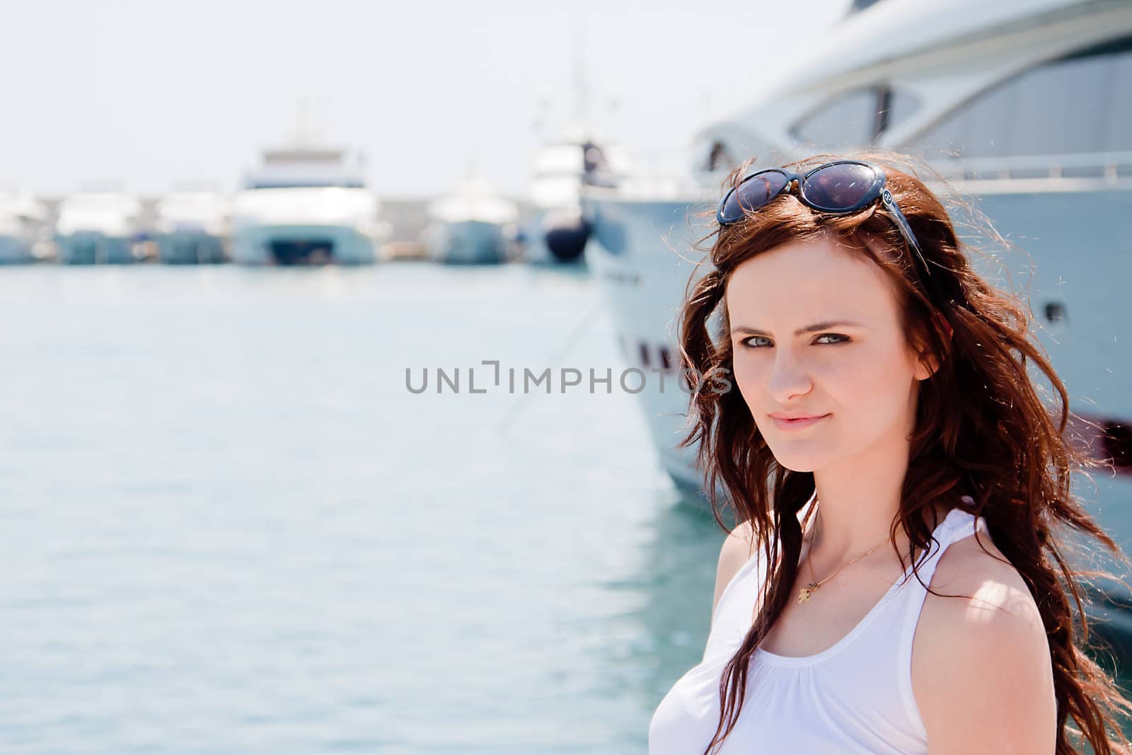 Photo of a young and beautiful girl against the backdrop of yachts in the port