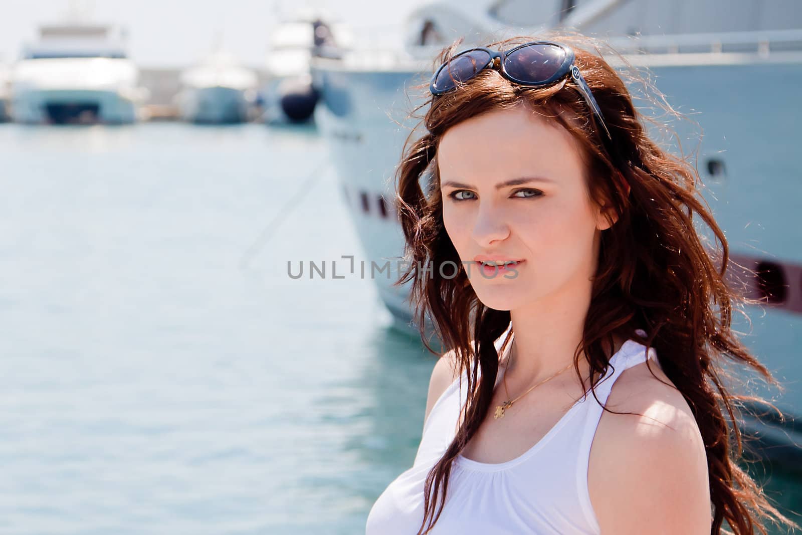 Photo of a young and beautiful girl against the backdrop of yachts in the port