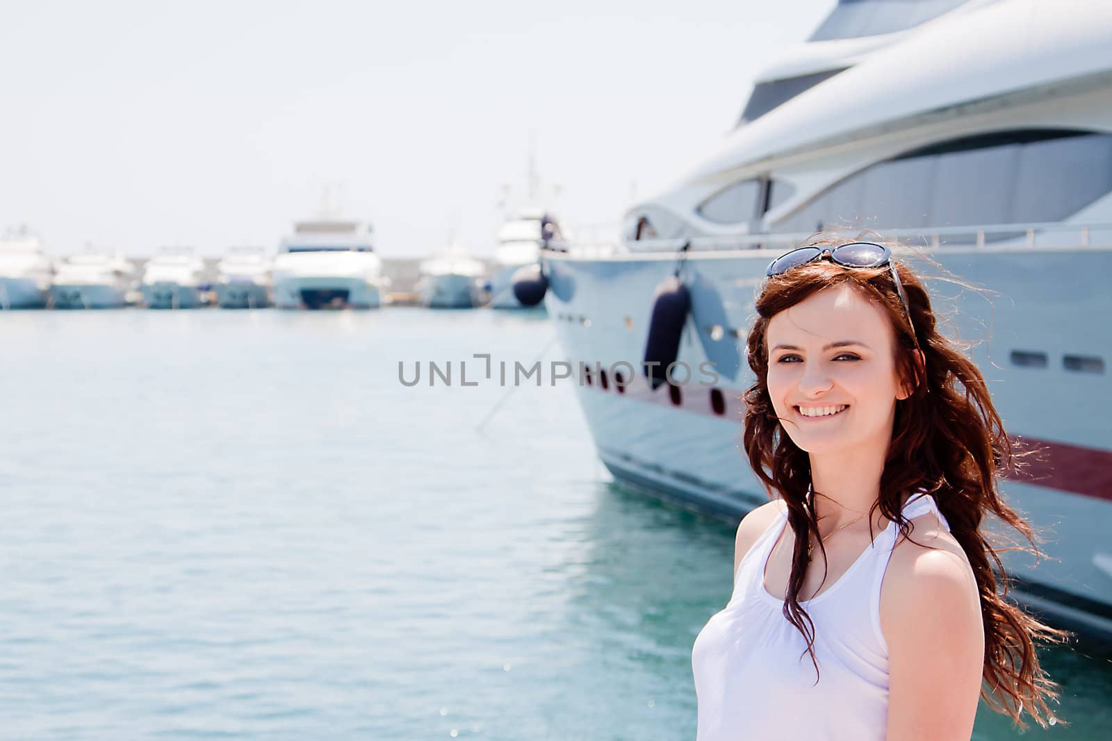 Photo of a young and beautiful girl against the backdrop of yachts in the port
