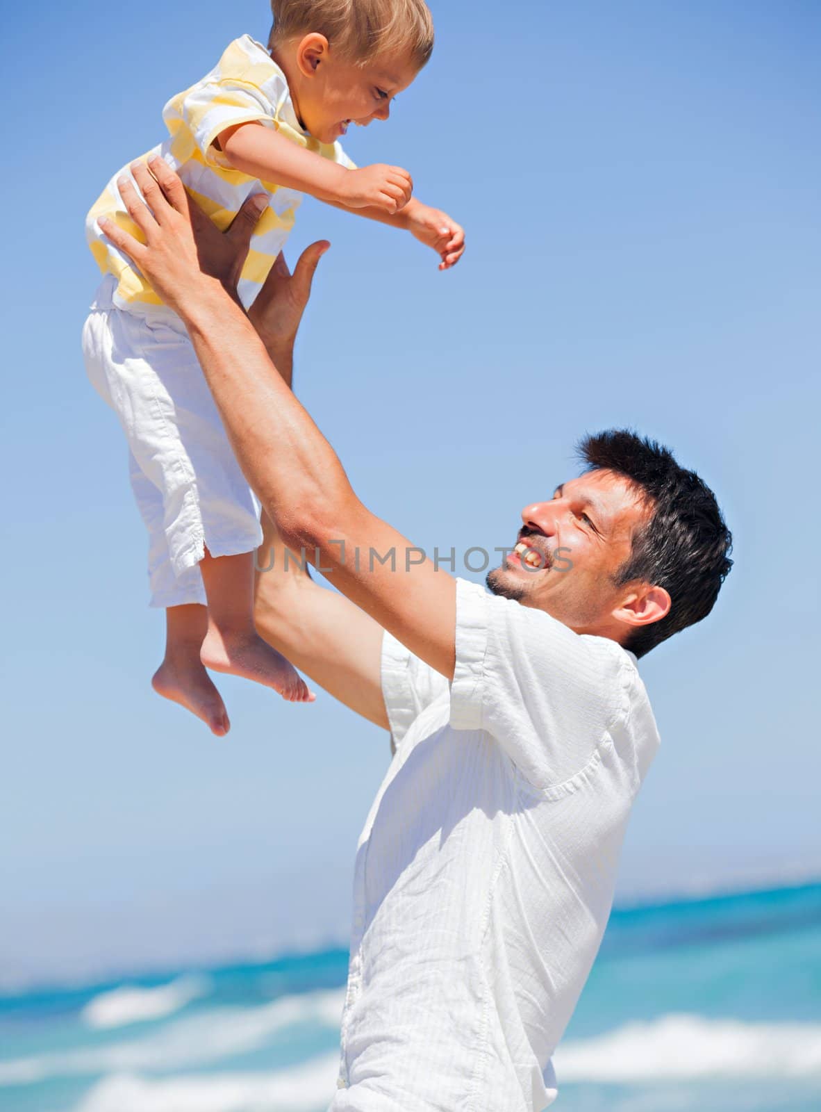 Father and son having fun on tropical white sand beach