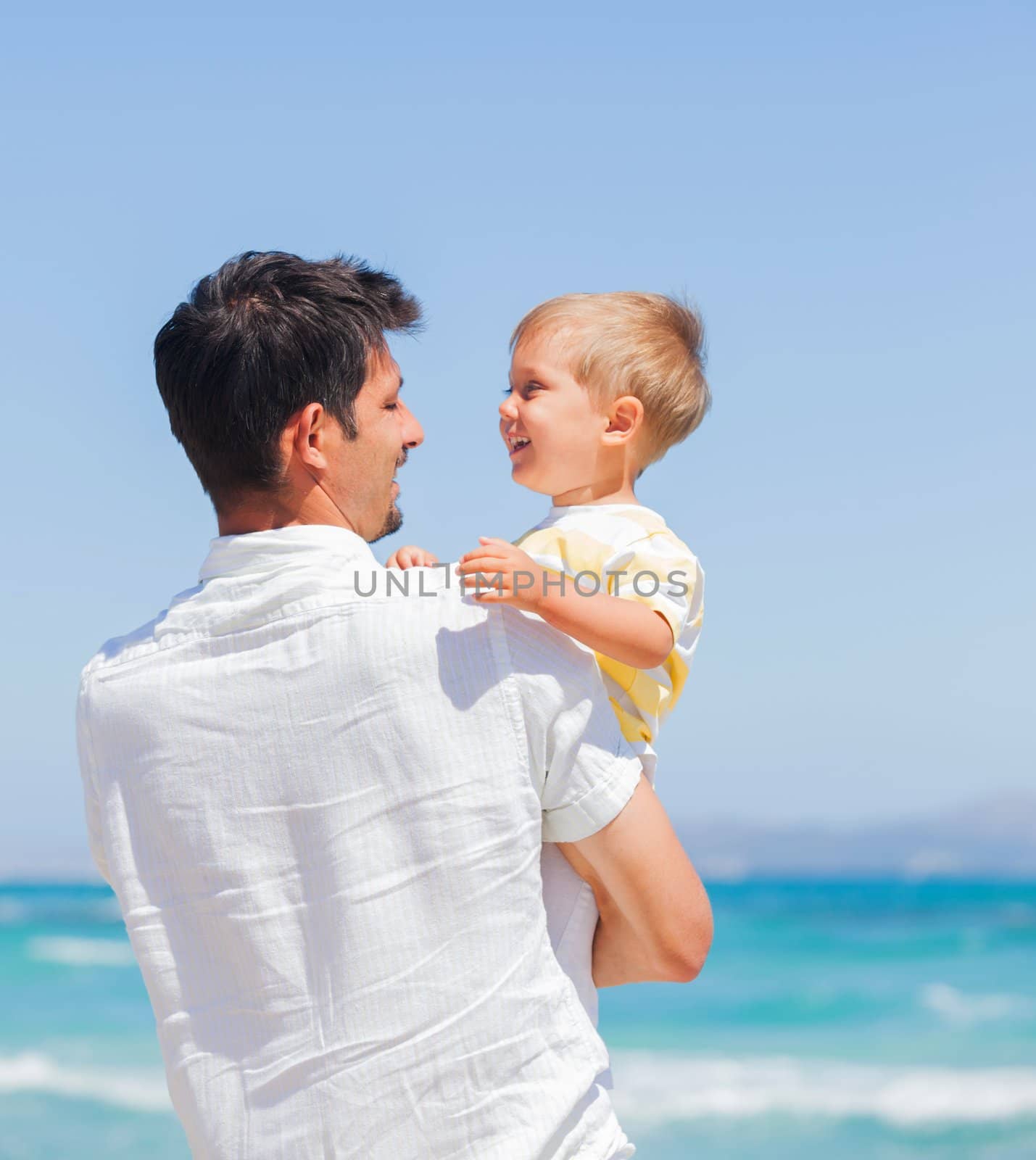 Father and son having fun on tropical white sand beach