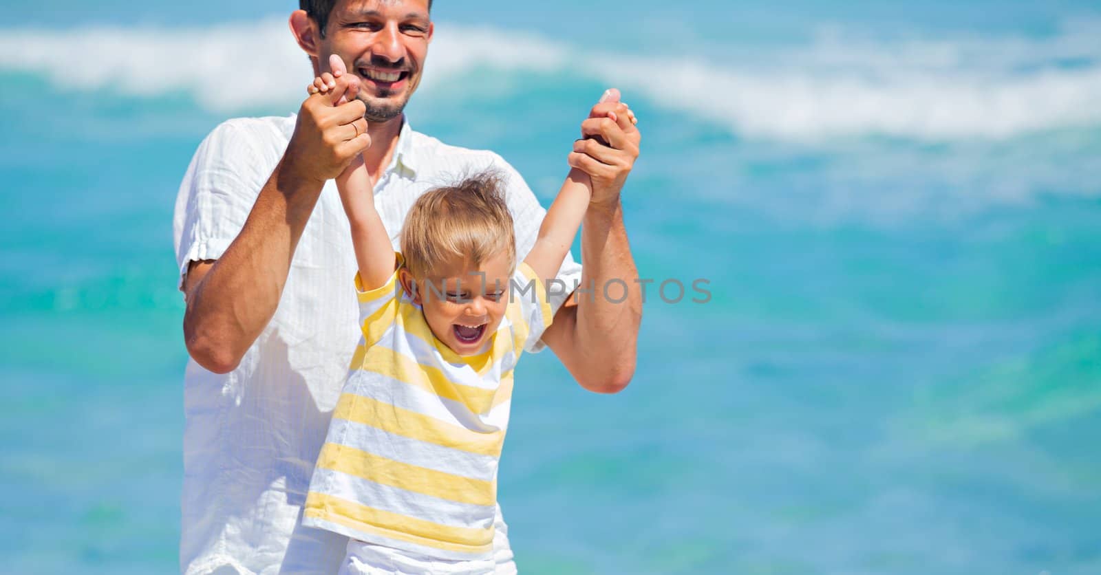 Father and son having fun on tropical white sand beach