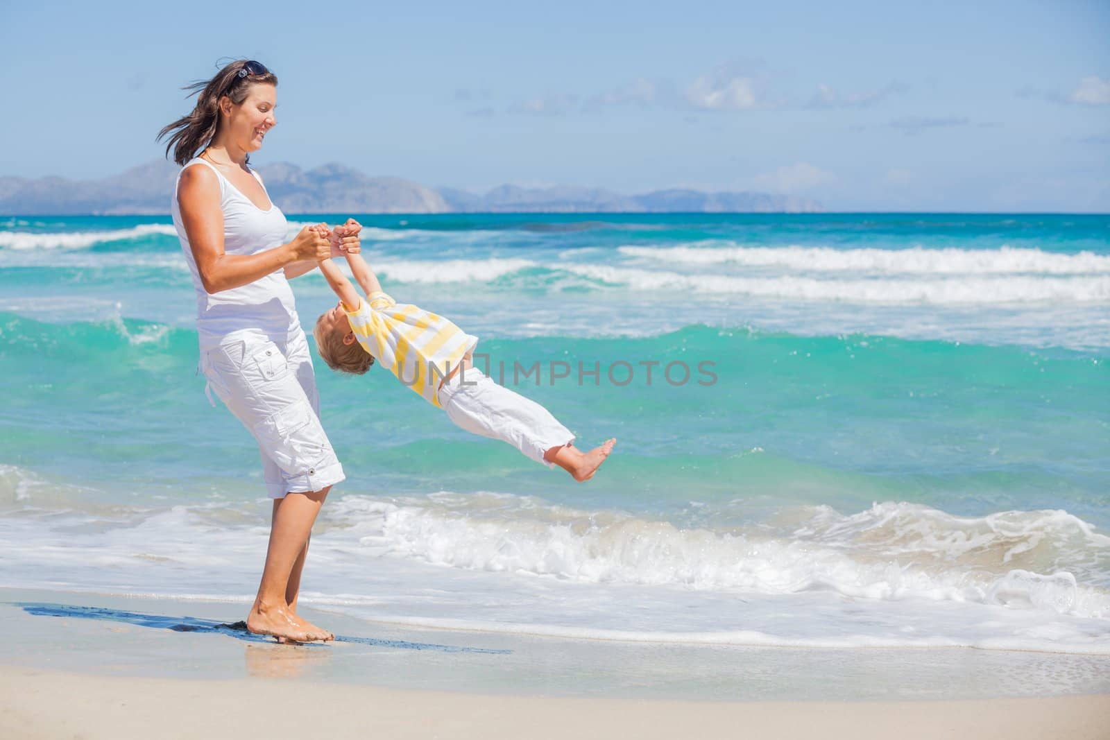 Mother and son having fun on tropical white sand beach