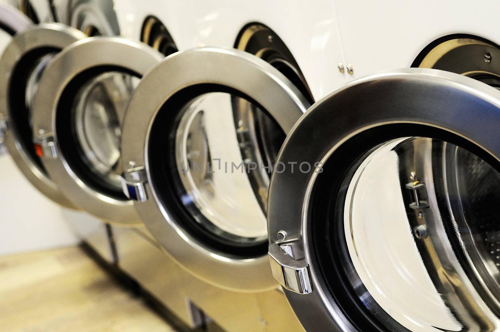 A row of industrial washing machines in a public laundromat 