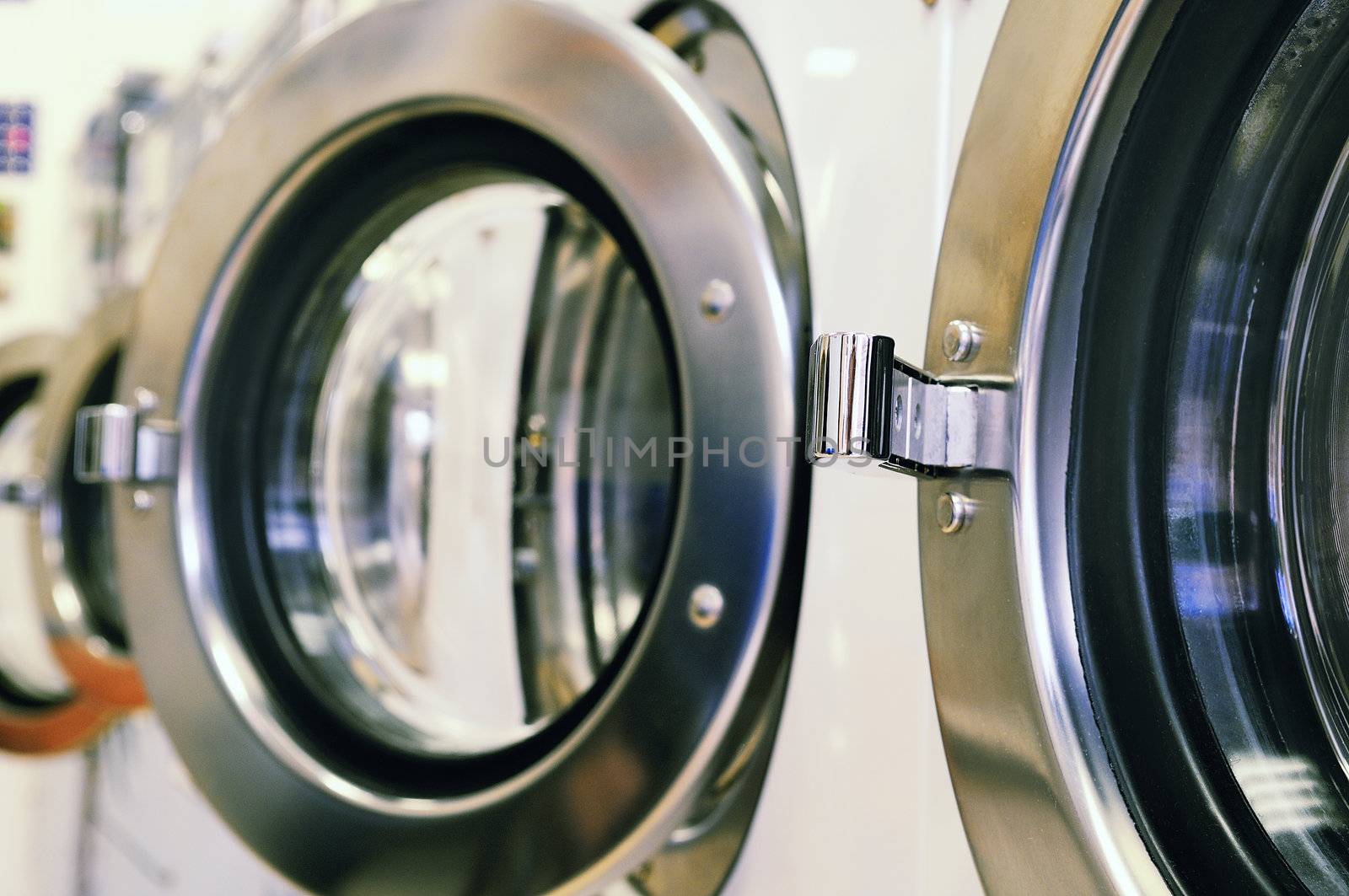 A row of industrial washing machines in a public laundromat 