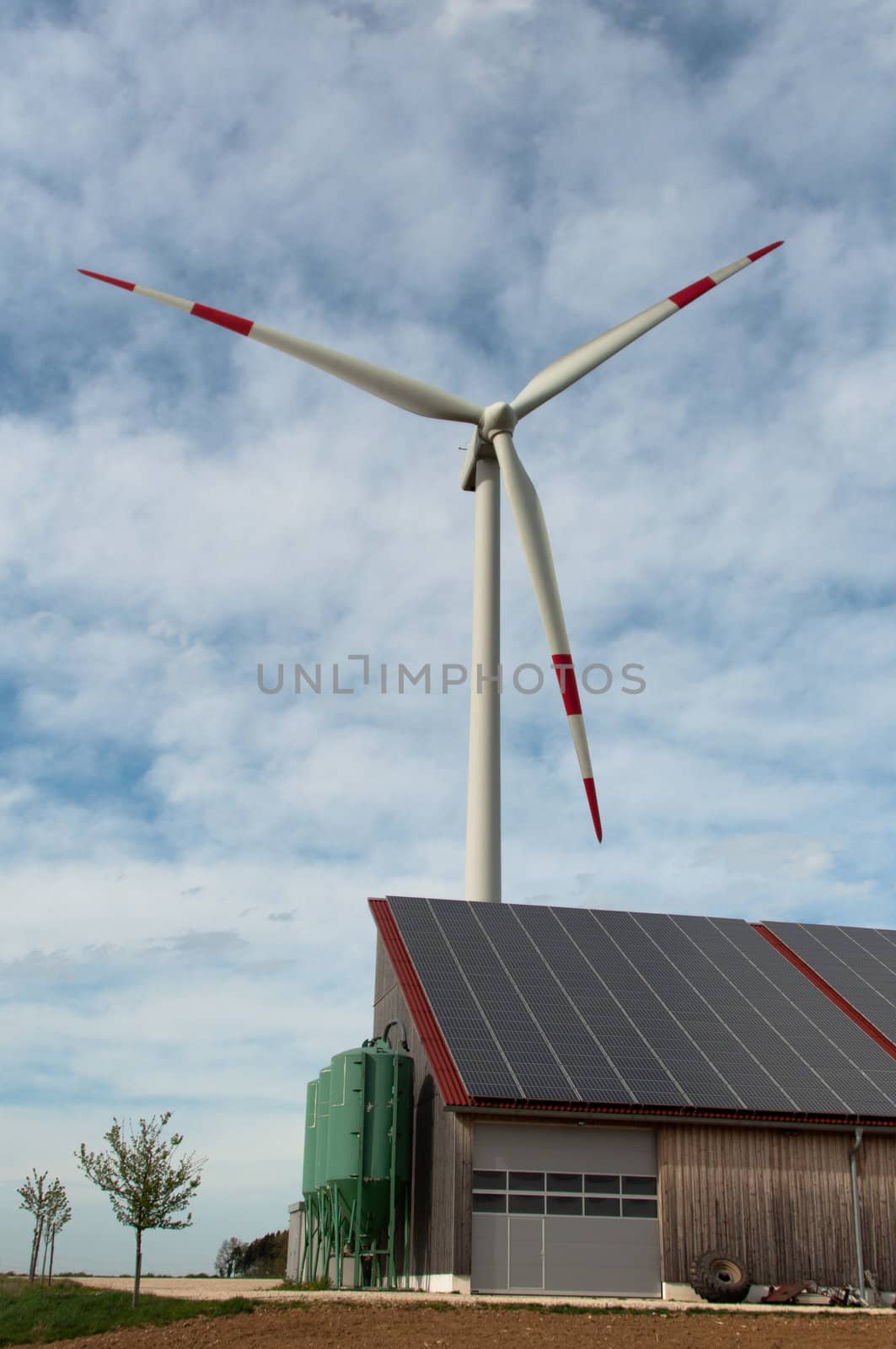 barn covered with solar panels and wind turbine in the background