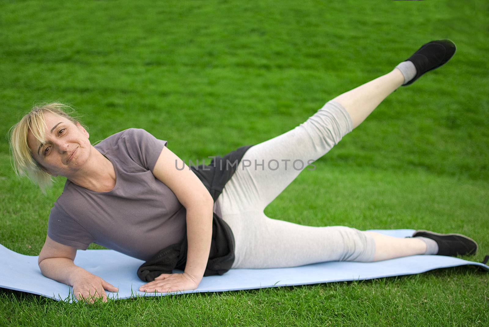 middle aged woman keeping fit with exercises in a park