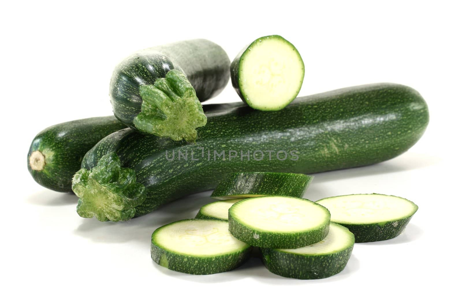 fresh sliced green and whole zucchini on a light background