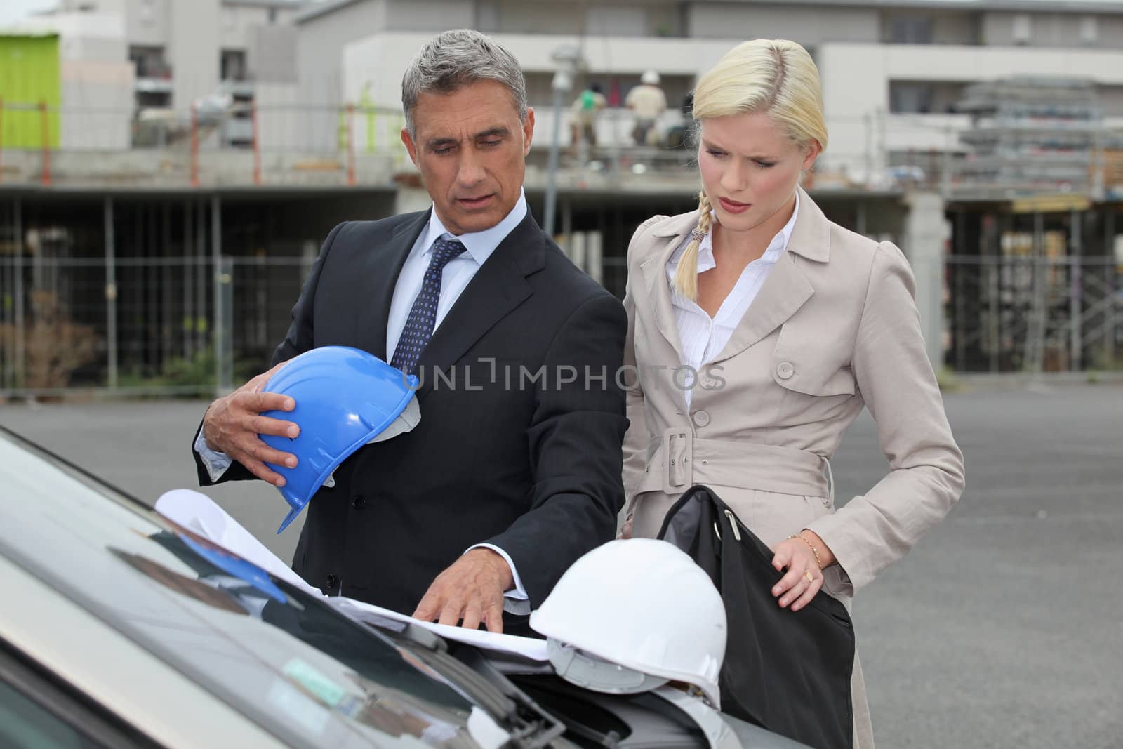 Male and female architects stood by car