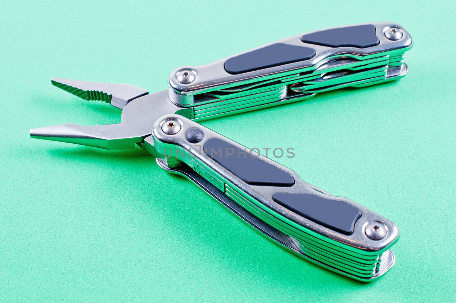Unfolded multi tool on green background