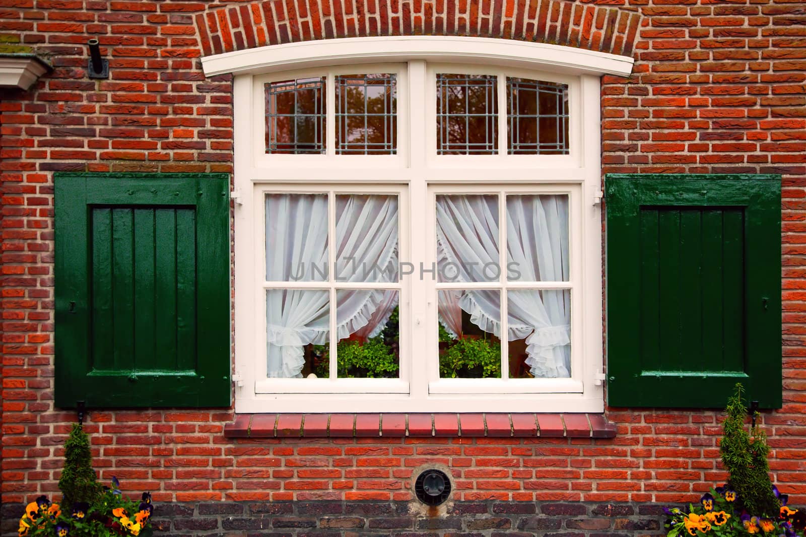 Old retro window with shutters on red brick house. Netherlands