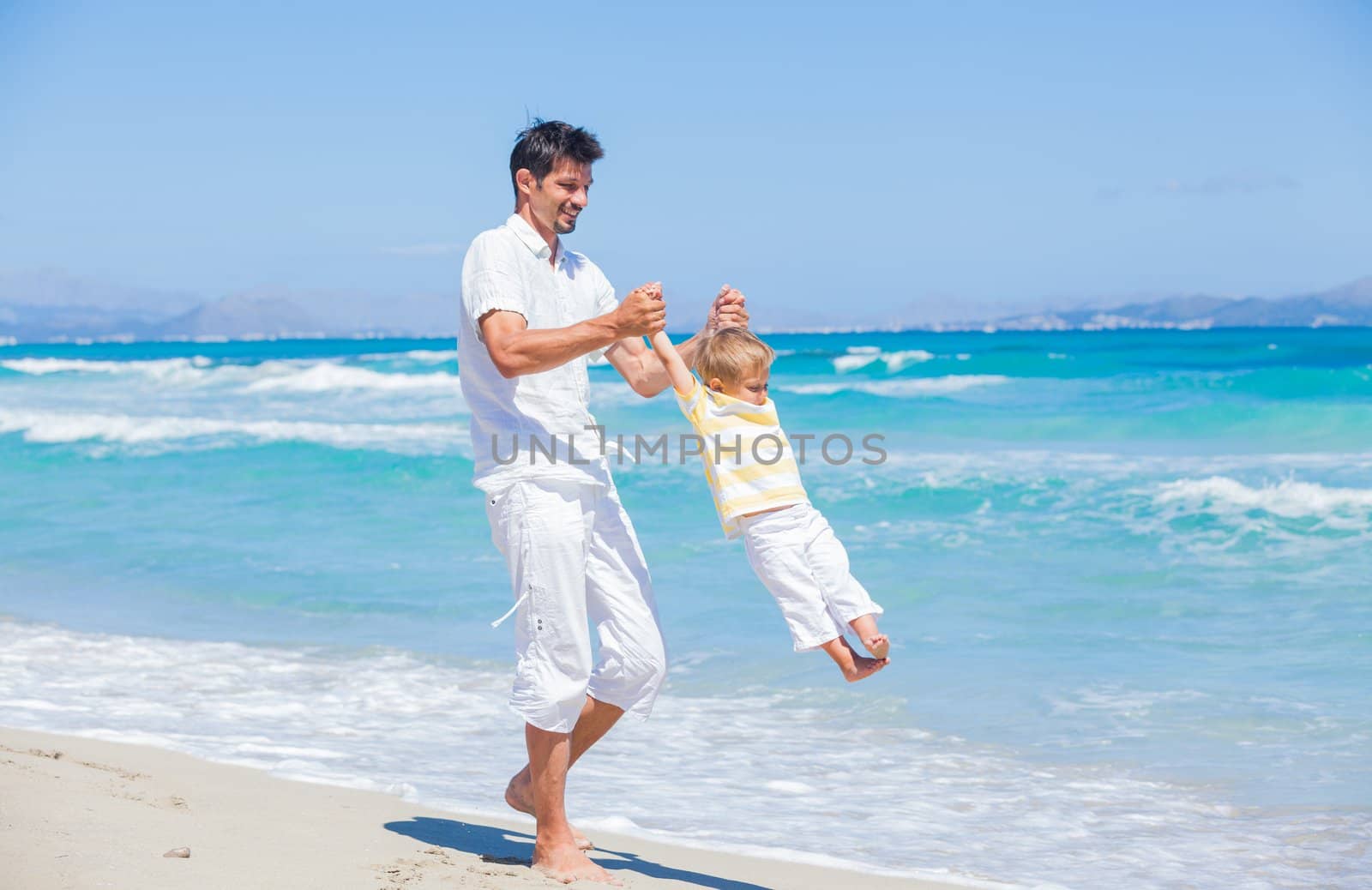Father and son having fun on beach by maxoliki
