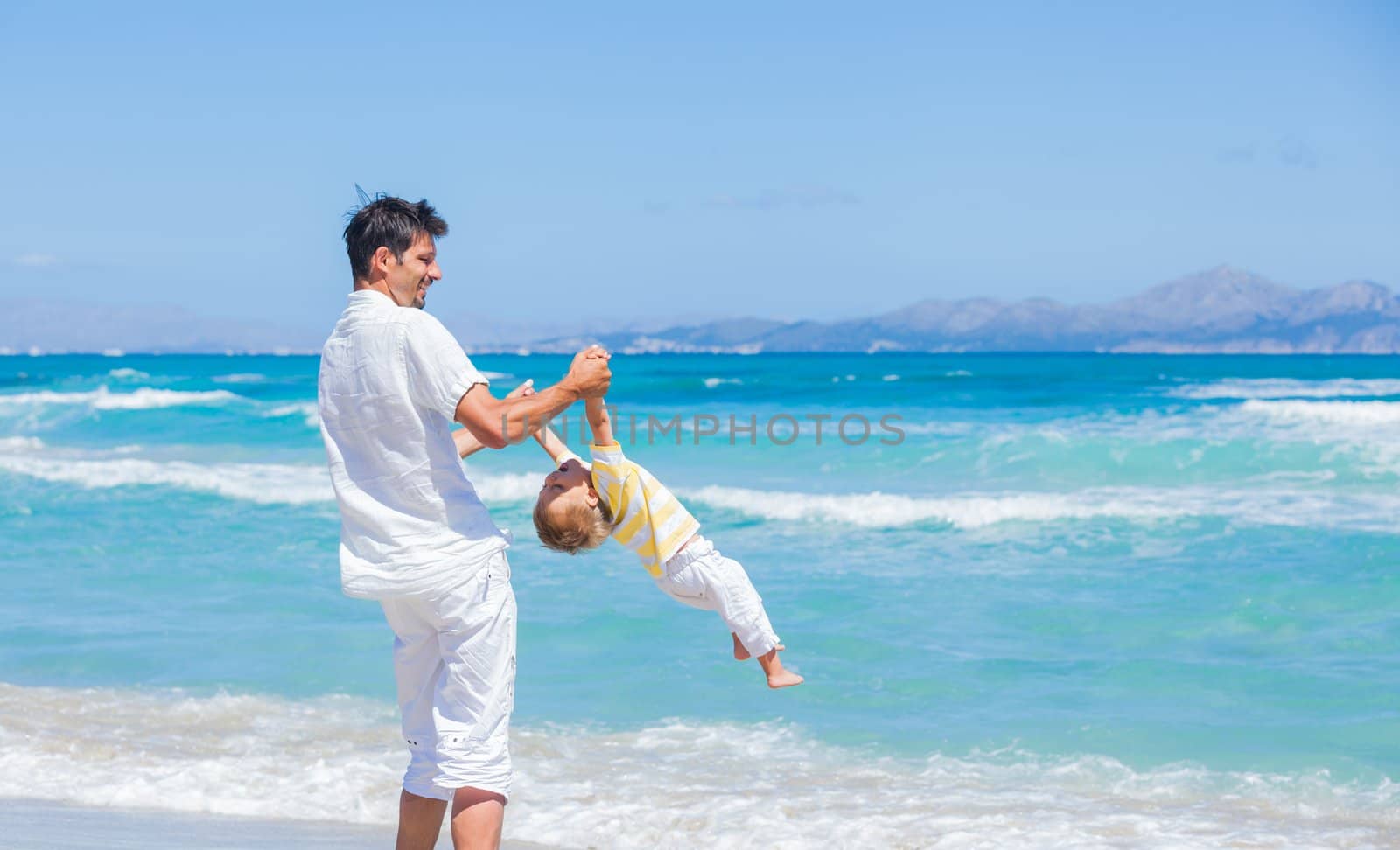 Father and son having fun on tropical white sand beach