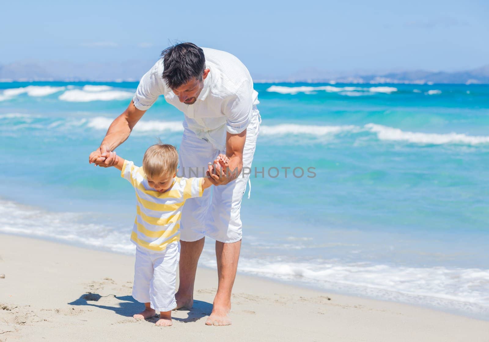 Father and son having fun on tropical white sand beach