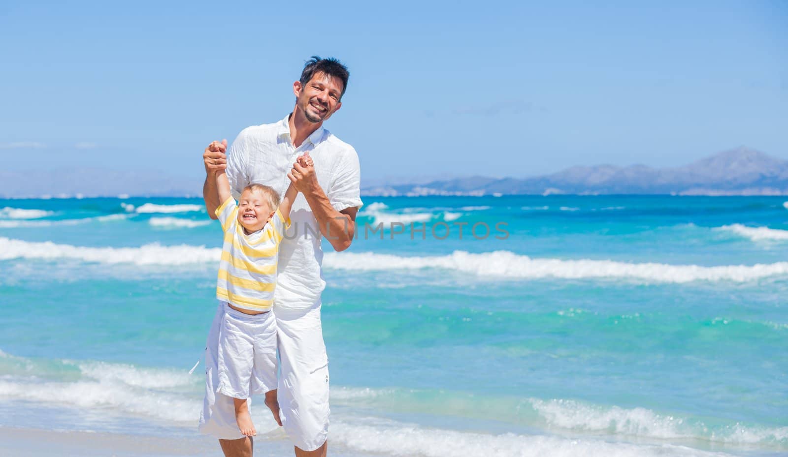 Father and son having fun on tropical white sand beach