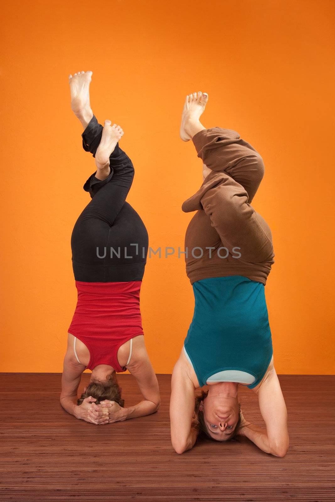 Two fit women in upside down position with interweaved legs