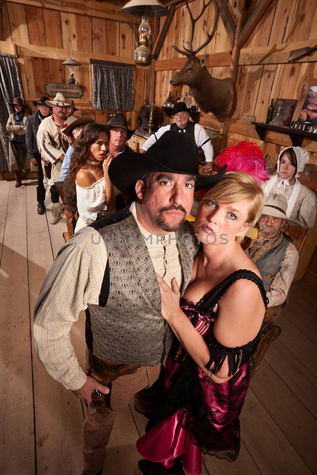 Serious old western couple in crowded saloon