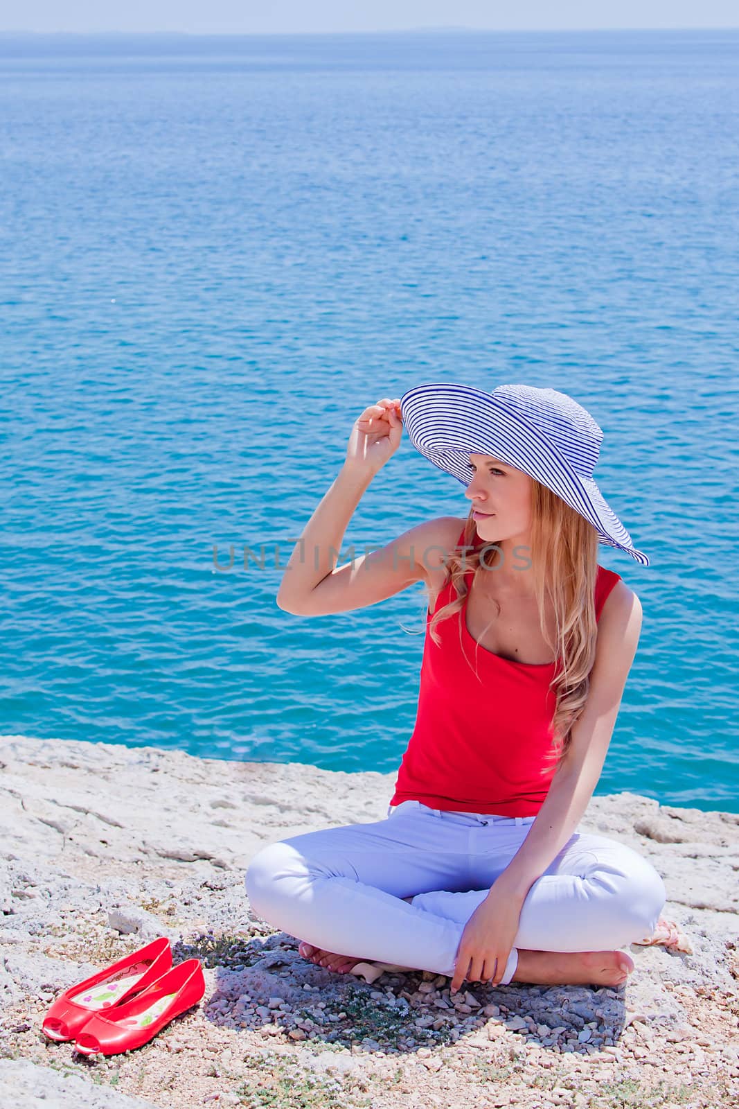 Young and beautiful girl resting on rocks against the sea