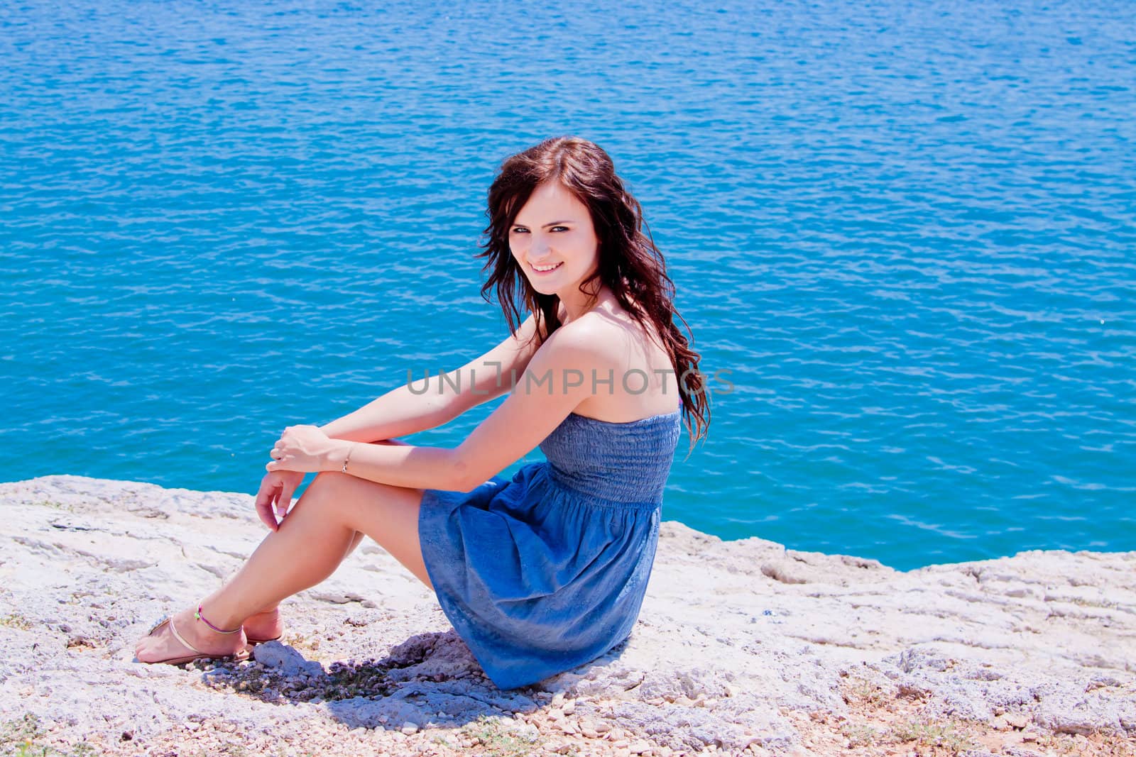 Young and beautiful girl resting on rocks against the sea