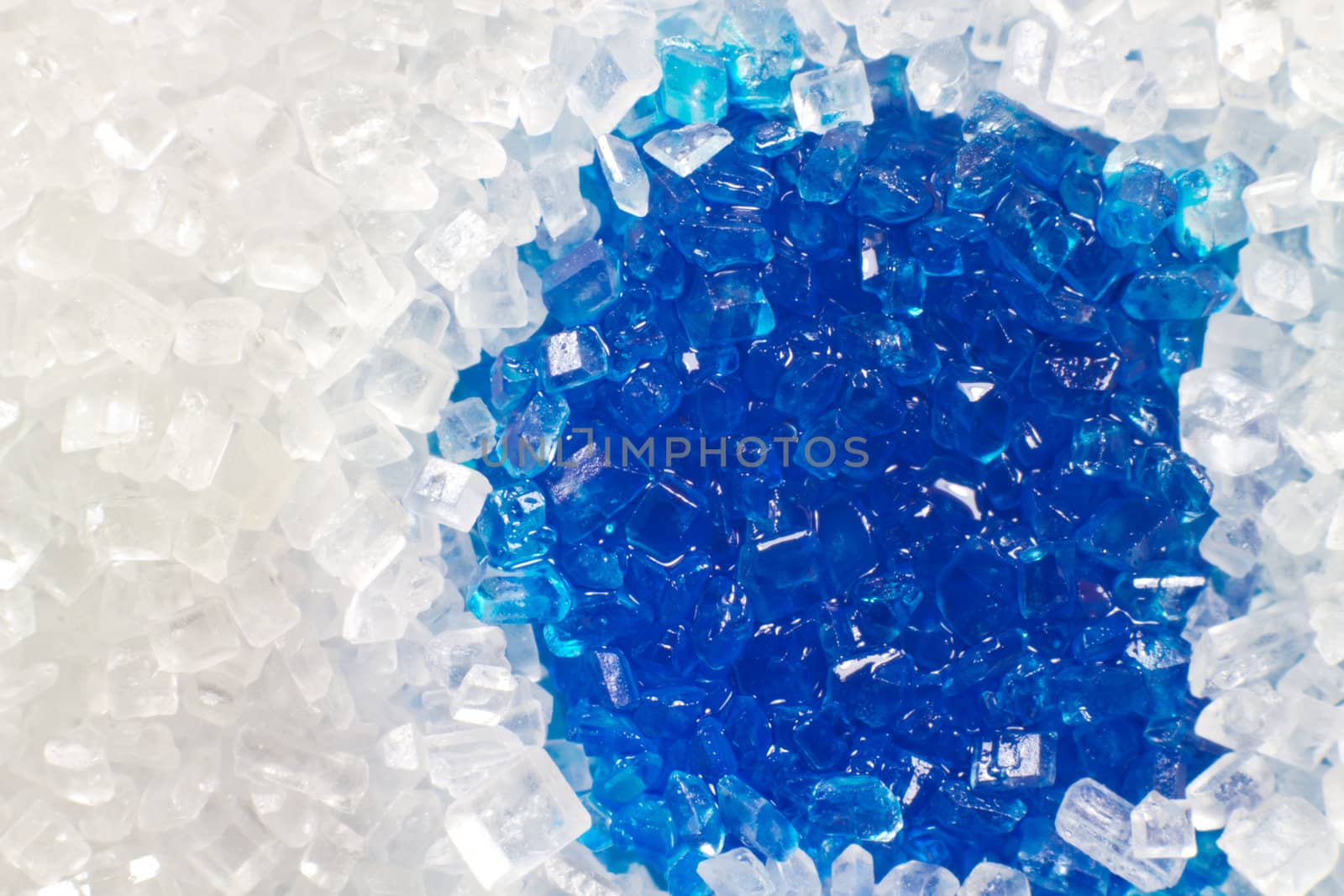 A macro picture of white sugar with blue liquid