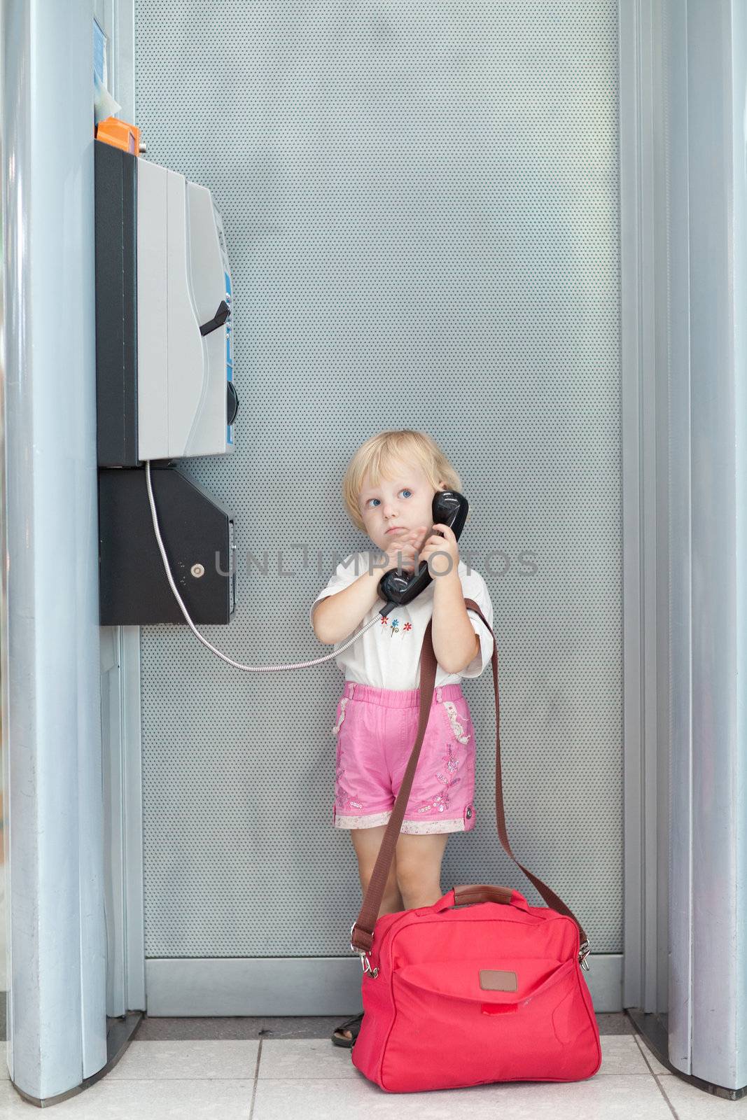 child talking the phone in the airport by vsurkov