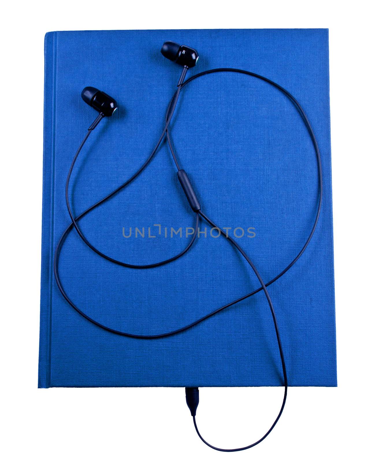 Black earbuds connected to blue notebook isolated
