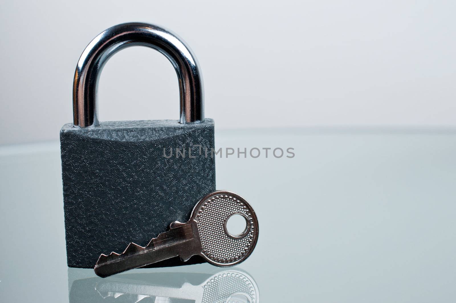 Padlock with a key on grey background