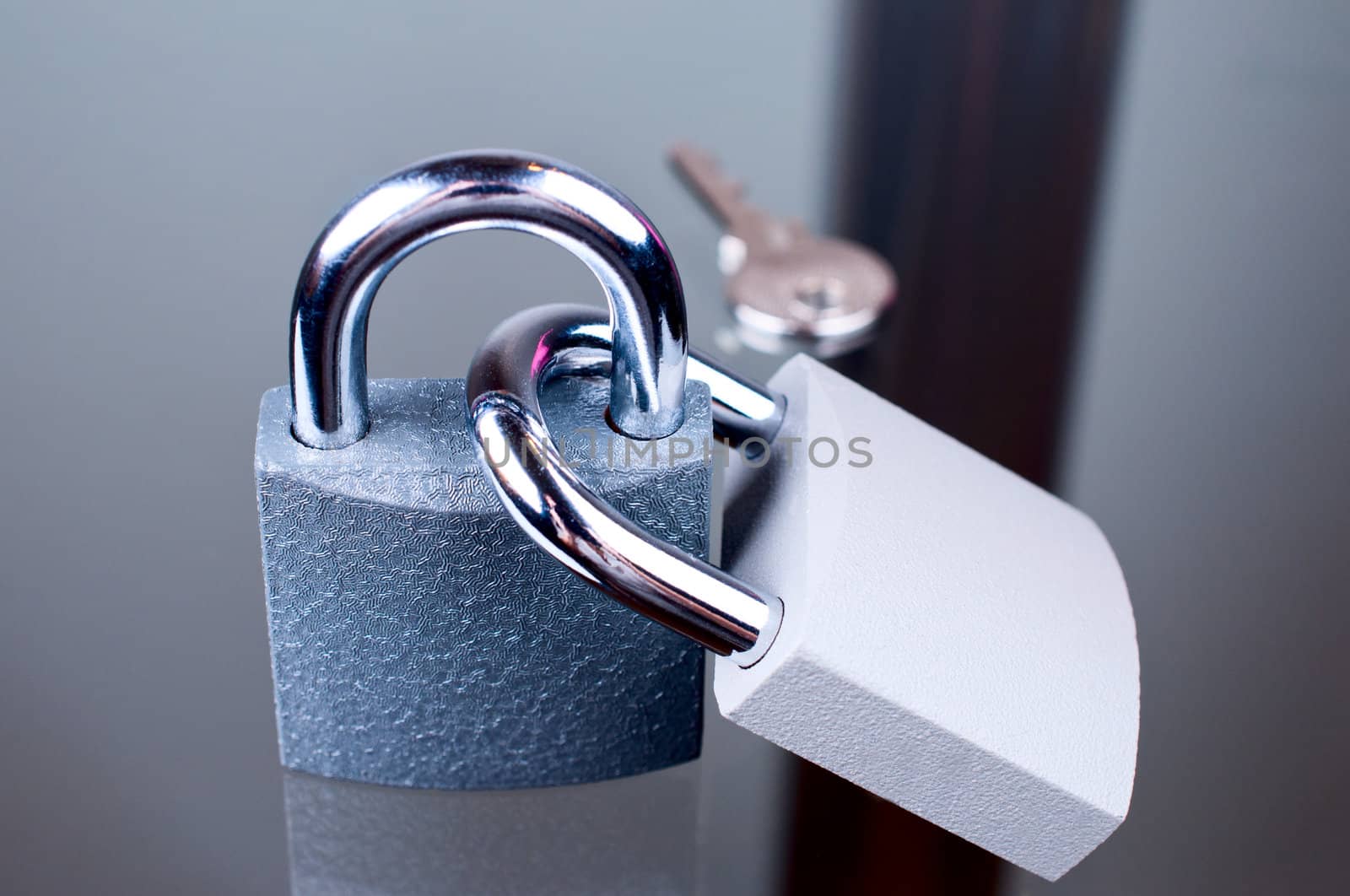 Two padlocks with a key on grey background