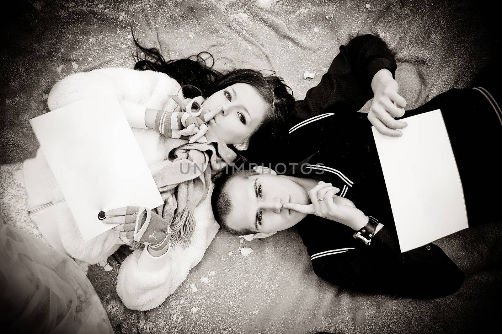 Couple laying on the ground with white papers for notes. Do not say. Secret.