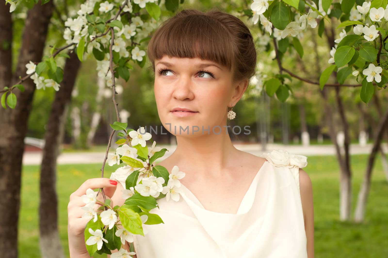 beautiful young brunette woman with the apple tree on a warm summer day