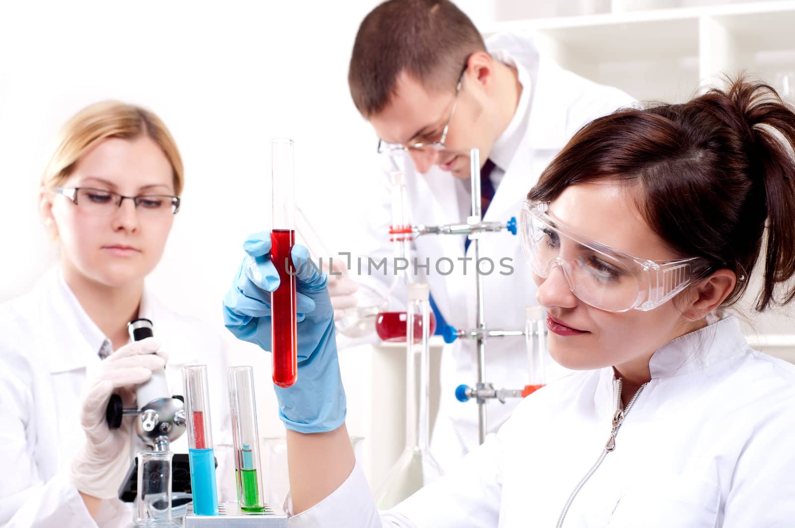 portrait of a beautiful woman chemist, looks at a test tube with red fluid