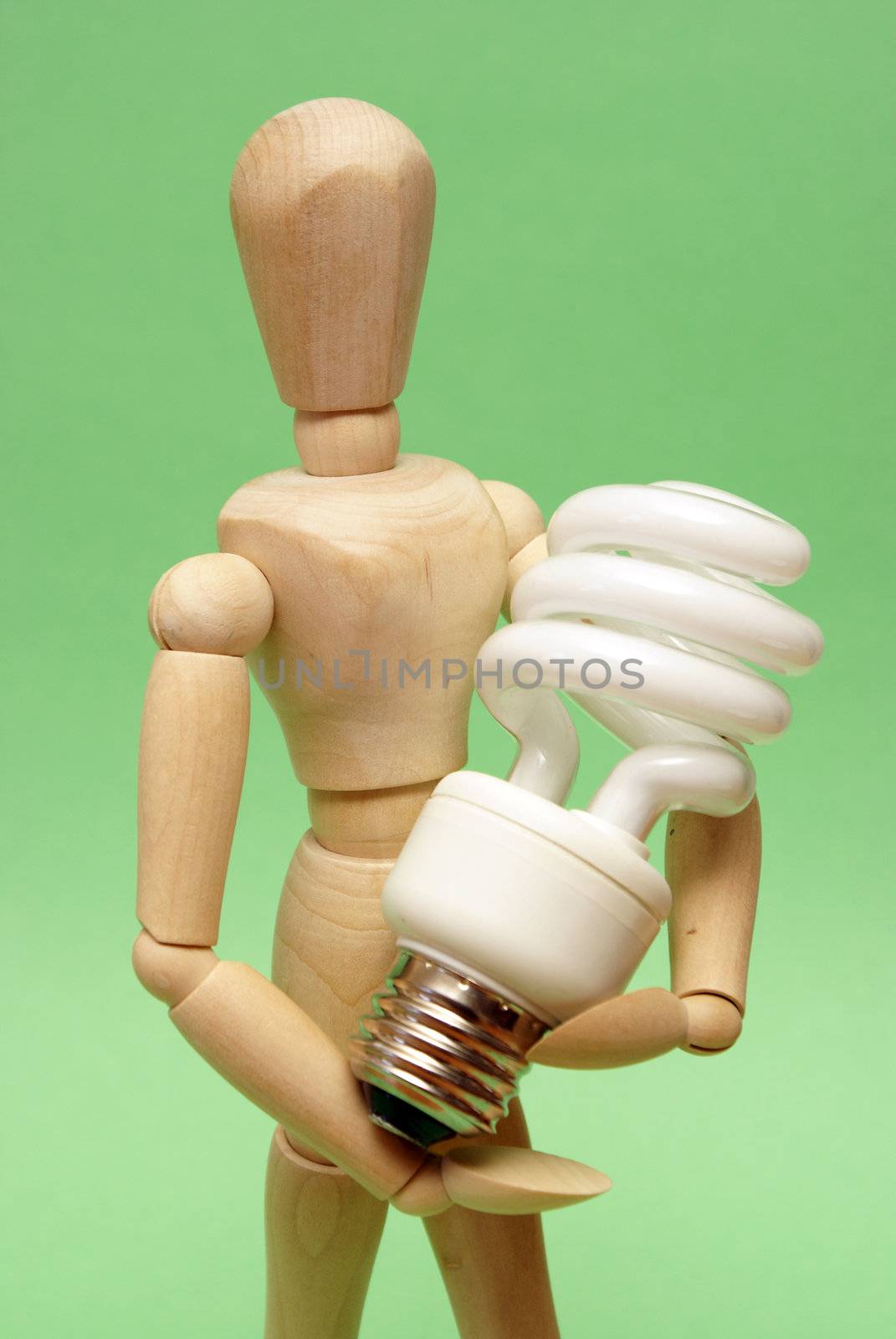 A wooden guy holds onto a modern cfl lightbulb for many ecological concepts.