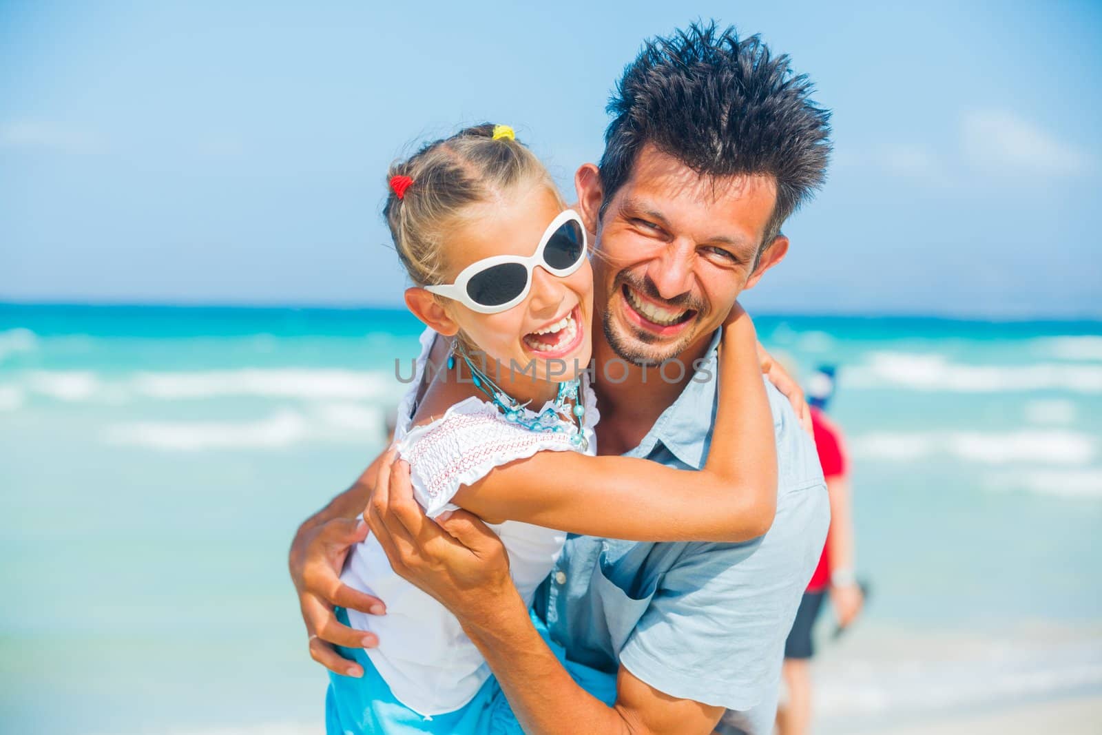 Father and daughter having fun on tropical white sand beach