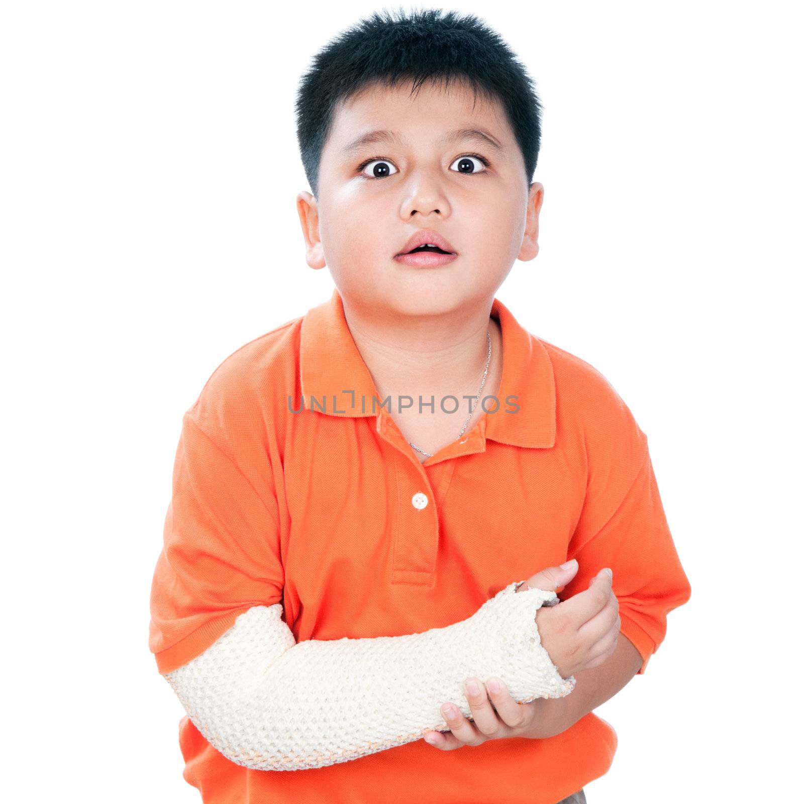 Portrait of a young Asian boy with fractured hand in plaster cast against white background.