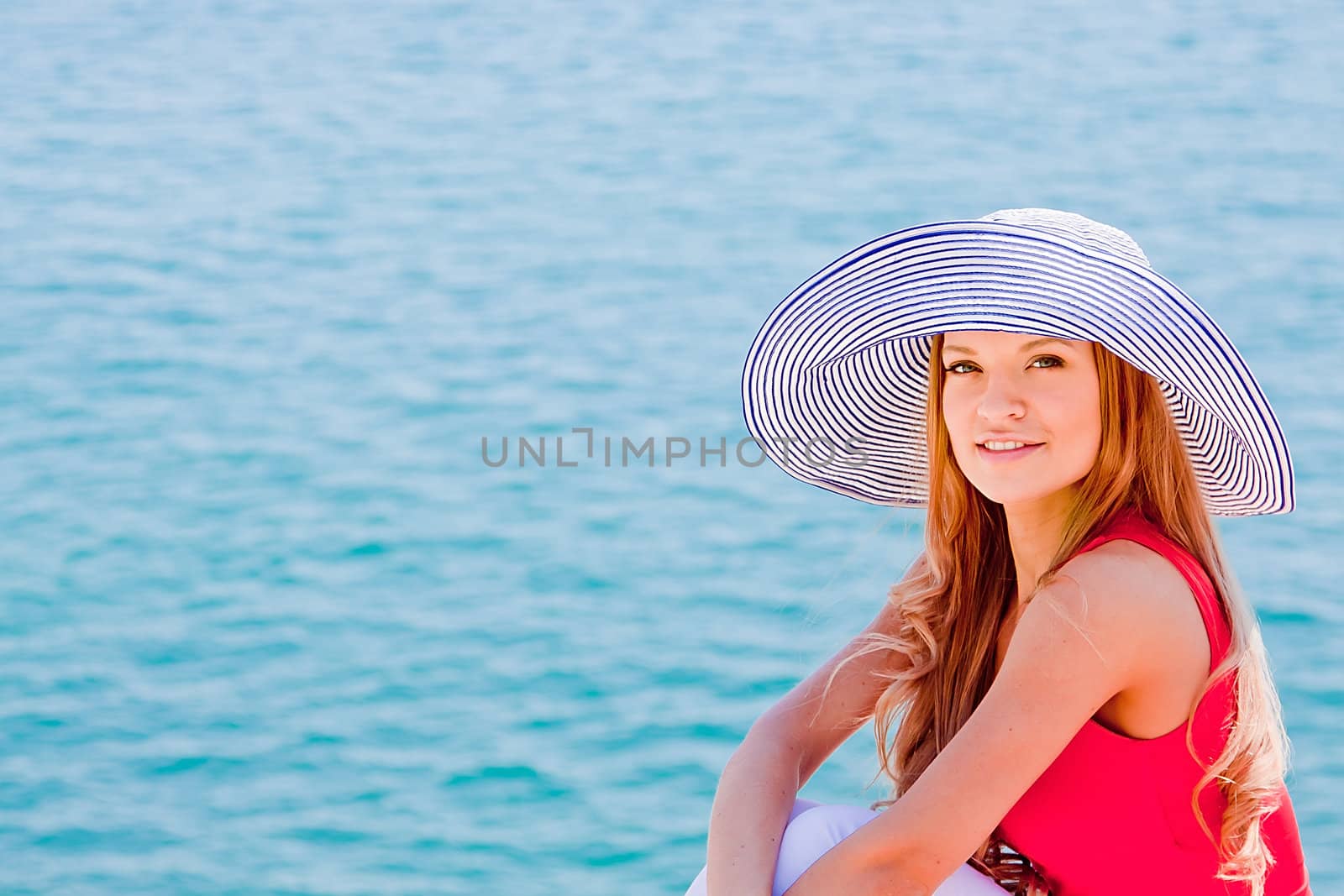 Young and beautiful girl resting on rocks against the sea