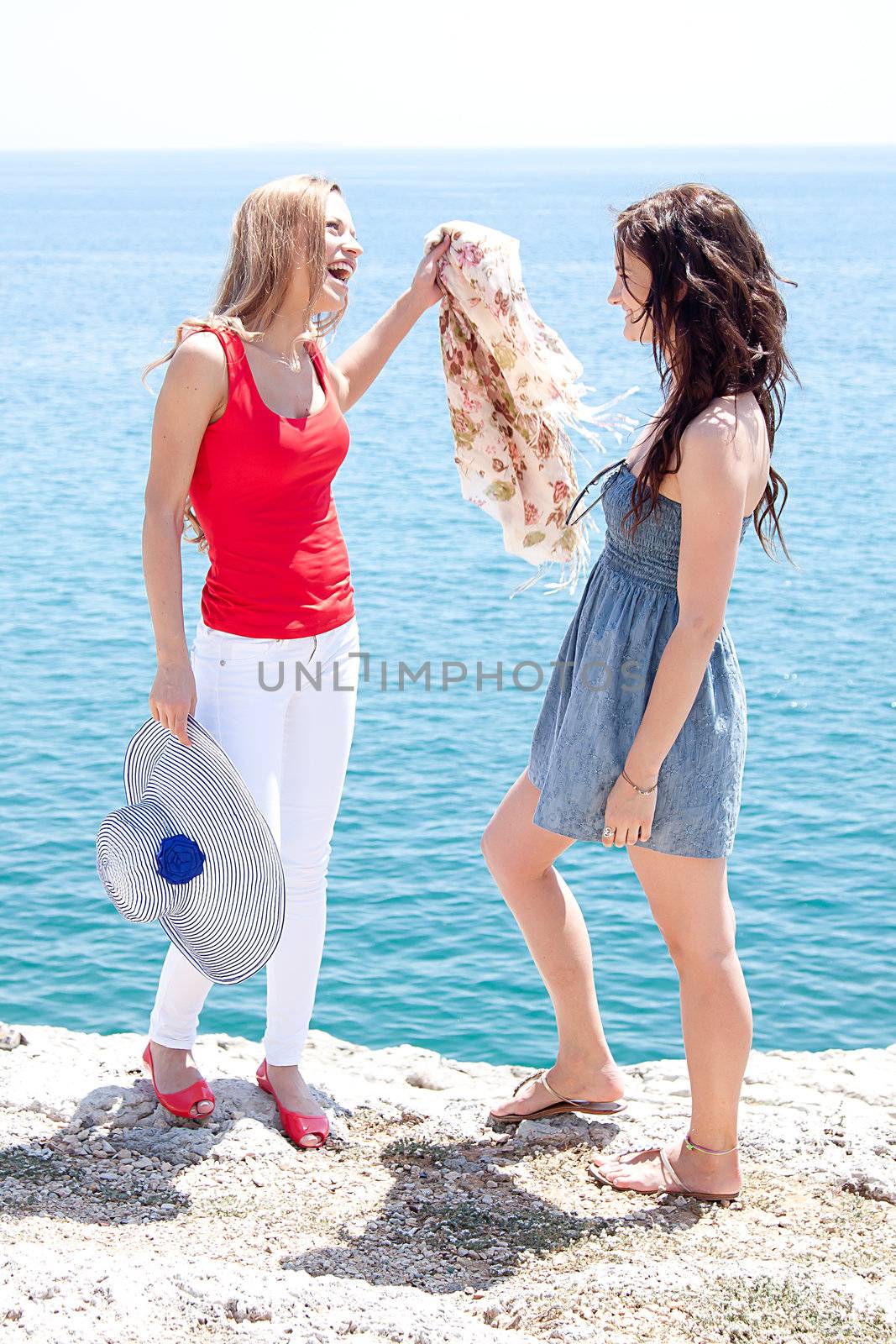 Two beautiful and young girl resting on a rocky coast