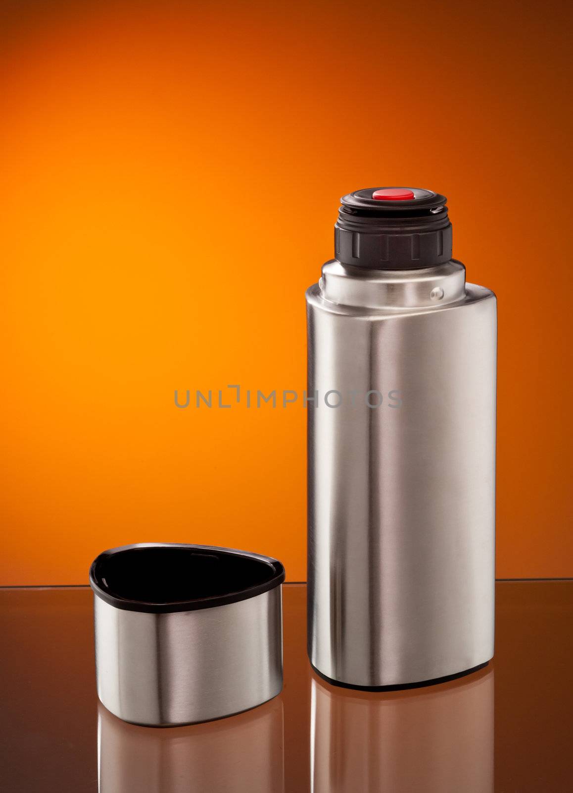 modern steel vacuum flask over orange background