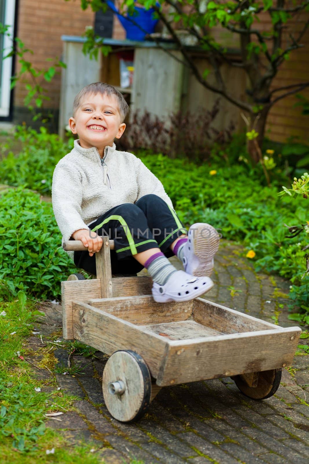 3 years old cute boy plays with toy tools in the garden. Vertical view