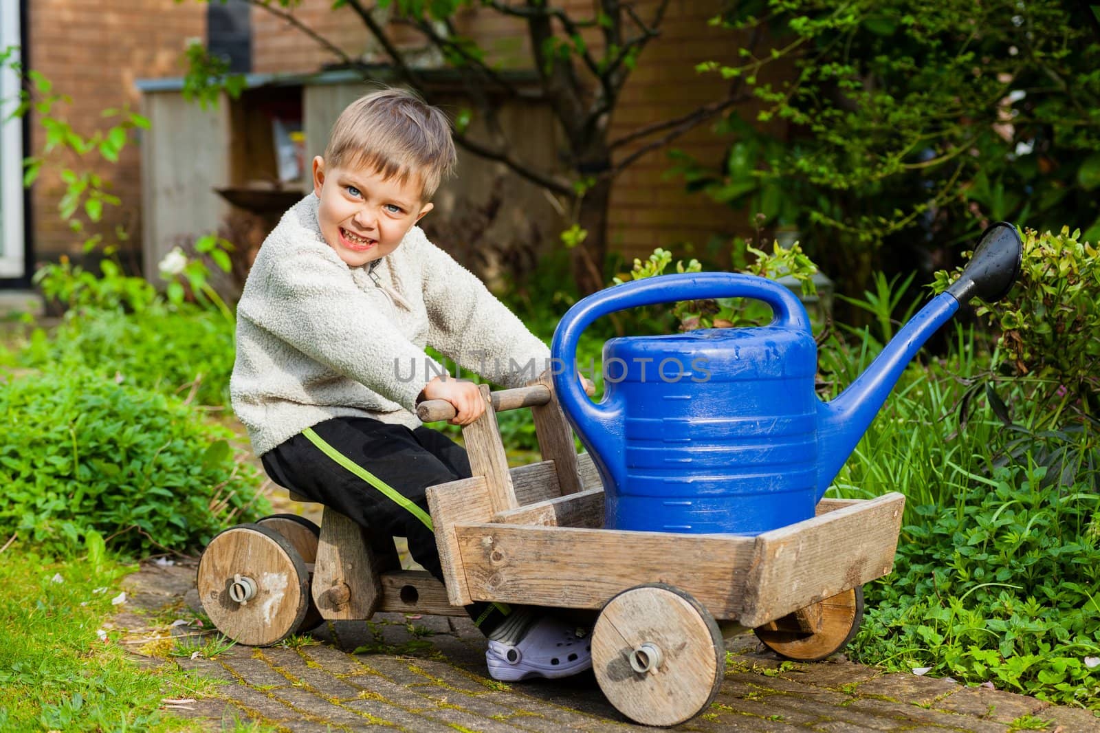 3 years old cute boy plays with toy tools in the garden.