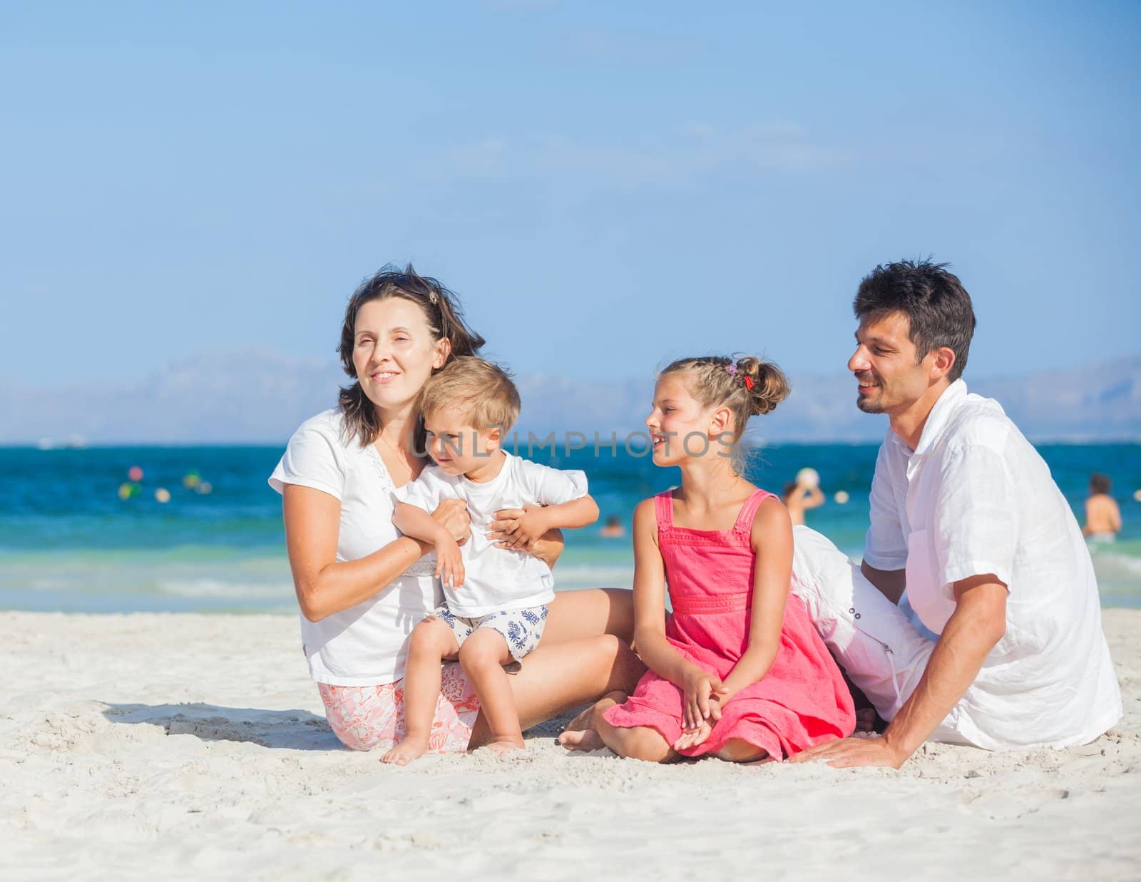 Family of four on tropical beach by maxoliki