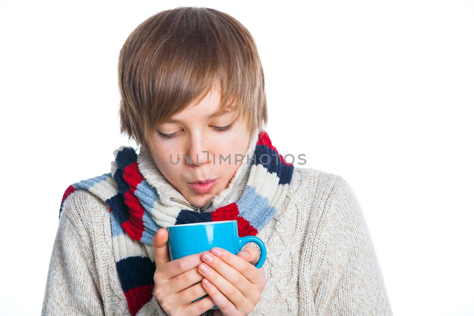 Portrait of young smiling cute frozen teenager in a scarf and with blue cup, isolated on white