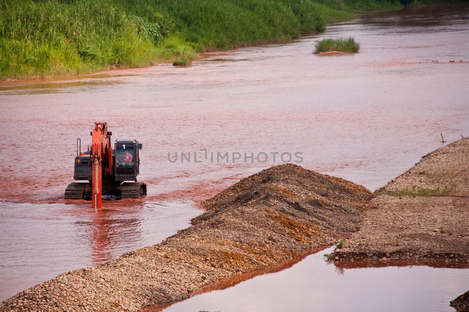 Excavator loader at river with raised bucket over blue sky by Yuri2012