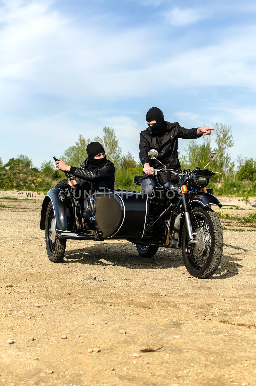 Two armed men riding a motorcycle with a sidecar